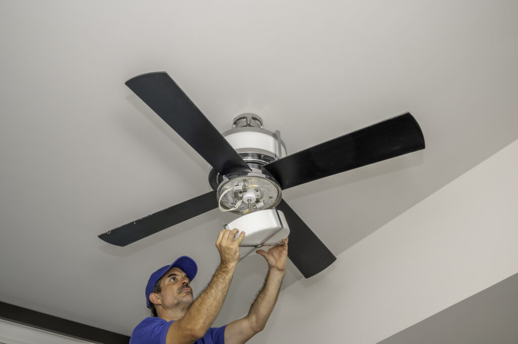 Ohio electrician installing a ceiling fan with light kit in Ohio home.